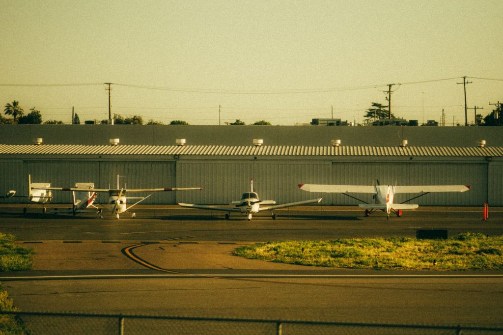 Four private airplanes parked on a sunlit airfield runway, captured at sunset.